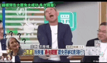 a man in a suit is making a funny face in front of a group of people in chinese .
