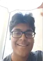 a young man wearing glasses and a gray shirt smiles for the camera