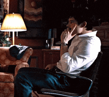 a man sitting in a chair with his hand on his face