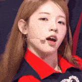 a close up of a woman wearing a microphone and a red shirt