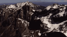 an aerial view of a mountain range with snow on the peaks
