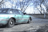 a green car is parked on the side of the road
