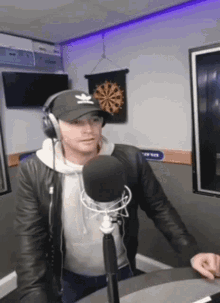 a man wearing headphones and an adidas hat is standing in front of a microphone ..