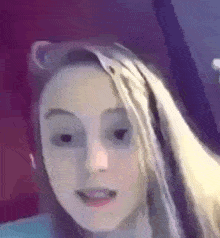 a close up of a girl 's face with a purple background .