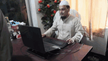 a man in a white hat sits at a desk with a laptop on it