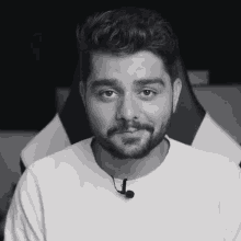 a man with a beard is wearing a white shirt with a microphone on his neck