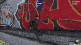 a man is walking down a street next to a wall with graffiti on it that says ' sss '