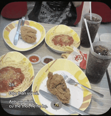 a person wearing an adidas shirt sits at a table with plates of food on it