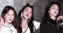three girls are standing next to each other on a stage and one of them has a bow in her hair .