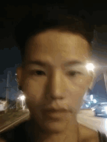 a close up of a man 's face with a street in the background