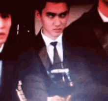 a man in a suit and tie is holding a microphone while standing in a dark room .