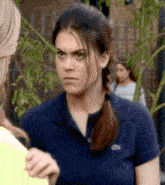 a woman wearing a blue shirt with a lacoste logo on it