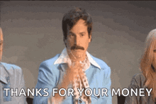 a man with a mustache is sitting in front of a group of people and says thanks for your money