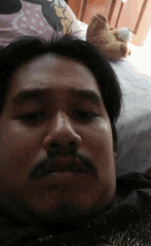 a man with a moustache is laying on a bed