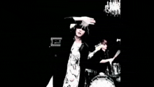 a man is playing a guitar in a dark room while another man is playing drums .