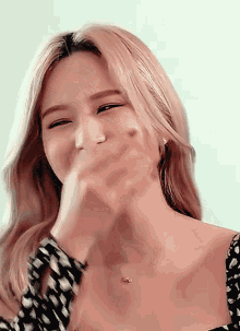 a woman with blonde hair is covering her mouth with her hands