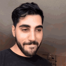a man with a beard wearing a black shirt looks at the camera