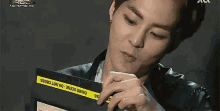 a man is holding a piece of paper that says crime scene do not cross on it .