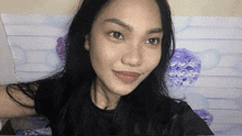 a woman with long black hair is taking a selfie in front of purple flowers