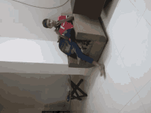 a boy in a red shirt with the letter v on it sits on a couch with his legs crossed