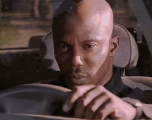 a man is driving a car and looking at the camera .