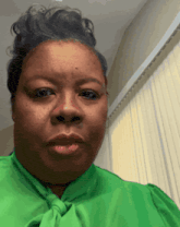 a woman wearing a green shirt and tie is making a funny face