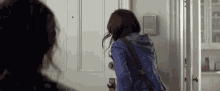 a woman in a blue jacket is walking into a doorway