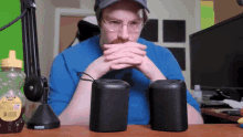 a man sitting at a desk with two rode speakers and a bottle of honey