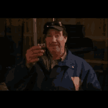 a man in a blue jacket is smoking a cigarette while standing in a dark room .