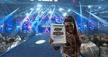 a woman is holding a clipboard that says aew on it in front of a crowd .