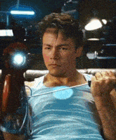 a man in a blue tank top is lifting a dumbbell