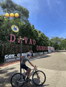 a man is riding a bike in front of a sign that says davao