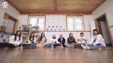 a group of girls sit on the floor in front of a sign that says twice on it