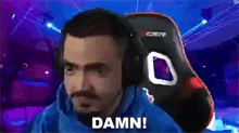 a man wearing headphones is sitting in a gaming chair and saying damn !