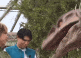 a man is standing next to a dinosaur statue with its mouth open