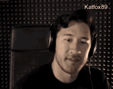 a man wearing headphones is sitting in a chair and rubbing his forehead .