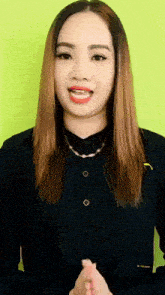 a woman wearing a black shirt and a necklace is smiling .