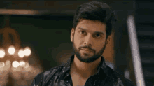 a man with a beard is standing in a room looking down .