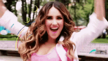 a woman with her arms in the air is smiling and laughing .