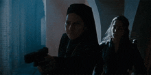a nun is holding a gun and another woman is standing next to her .