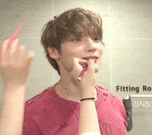 a man in a pink shirt is being brushed by a woman in front of a wall that says fitting room
