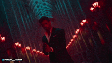 a man in a suit is standing in a dark room with the hashtag pranay varma