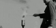 a black and white photo of a man standing next to a bottle .
