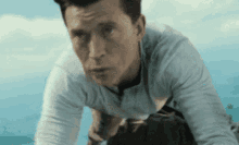 a man in a white shirt is kneeling down in front of a blue sky