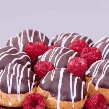 a bunch of donuts with chocolate icing and raspberries on top