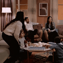 a group of people are gathered in a living room with a man sitting on a couch