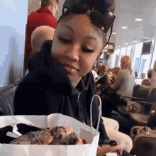 a woman wearing sunglasses holds a bag of food