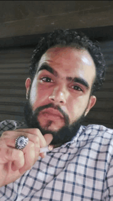 a man with a beard and a ring on his finger holds a cigarette