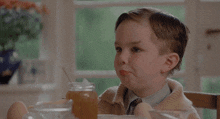 a little boy is sitting at a table with eggs and a jar of honey