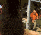 a man in an orange shirt is standing in front of a machine